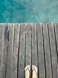 Low section of woman on boardwalk by swimming pool