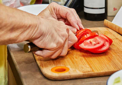 Woman cuts tomatoes for cooking at home using recipe from the internet