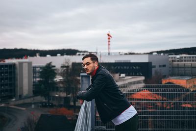 Side view of man standing by railing in city