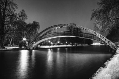 Illuminated bridge over river against sky at night