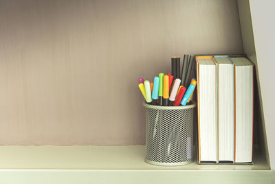 Close-up of colored pencils on table against wall at home