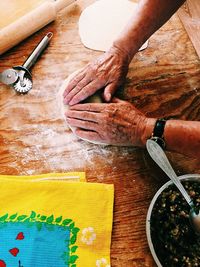Cropped hands of man kneading dough on wooden table