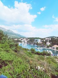 Scenic view of river by cityscape against sky