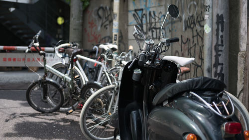 Bicycles and motor scooter parked by wall