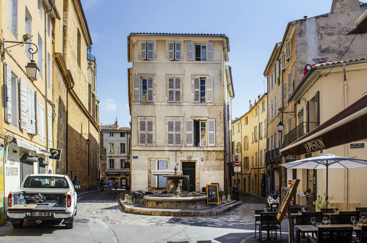 CARS ON ROAD BY BUILDINGS AGAINST SKY