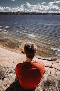 Rear view of man sitting at beach