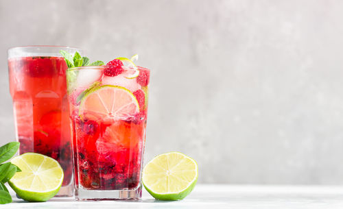 Cold pink non-alcohol cocktail with raspberry, lime, mint and ice cubes.