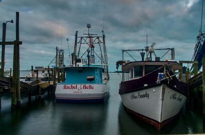 Boats moored at harbor against sky