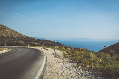 Scenic view of road by mountains against sky