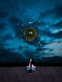 Man sitting on pier over sea at night