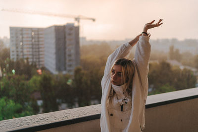 Portrait of young woman against building in city