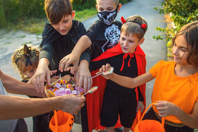 Midsection of woman giving candies to kids