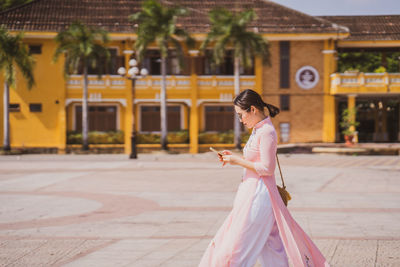 Side view of woman walking on street in city