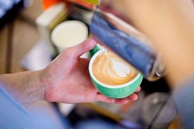 Close-up of barista decorating milk froth with floral pattern