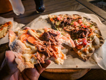 Close-up of hand holding pizza on table