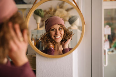 Happy fashion designer adjusting headband while looking in mirror