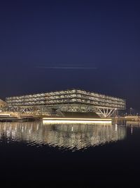 Illuminated bridge over river against sky at night