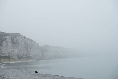 Rear view of man walking on sea against clear sky