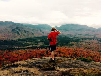 Rear view of man standing on mountain against sky