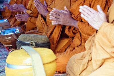 Midsection of monks praying while sitting by baskets