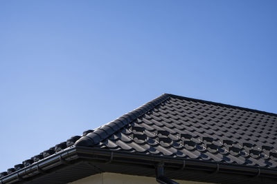 Low angle view of building roof against clear blue sky