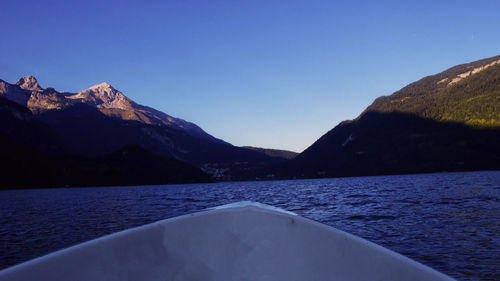 Scenic view of lake and mountains against clear blue sky