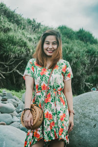 Portrait of smiling young woman standing against plants