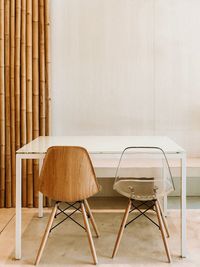 Empty chairs and table against wall