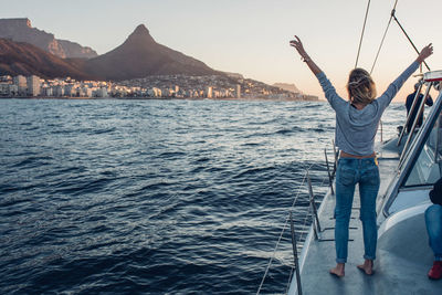 Rear view of woman standing on sailboat in sea