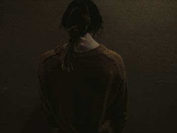 Rear view of sad woman standing against wall