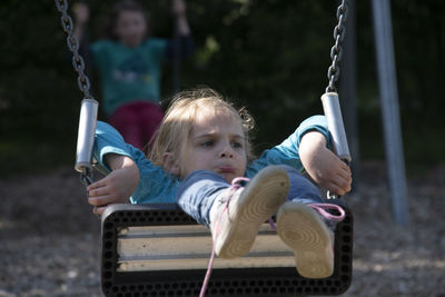 Rear view of people sitting on swing at playground