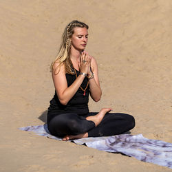 Young woman practicing yoga on the beach in newborough, north wales, uk