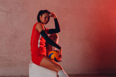 Portrait of young woman standing against wall