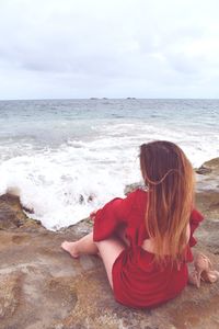 Woman looking at sea shore against sky