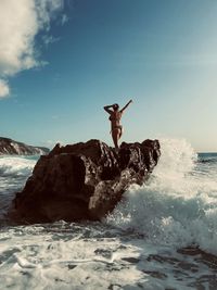 Rear view of man with arms raised in sea against sky