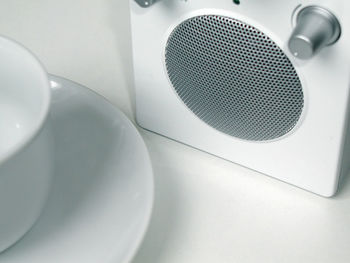 High angle view of white coffee cup and saucer by speaker on table