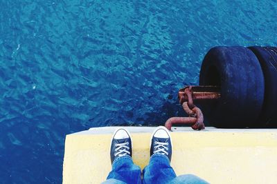 Low section of man standing on pier over sea