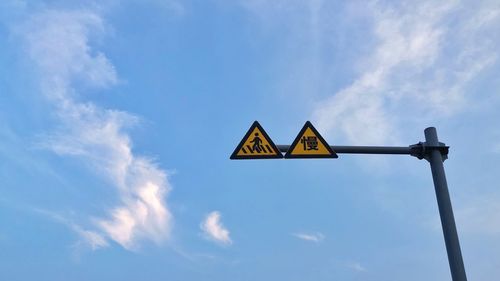 Low angle view of road sign against blue sky