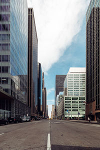 City street by modern buildings against sky