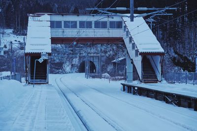 Snow covered railroad tracks by building during winter