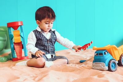 Portrait of boy playing with toy while sitting at beach