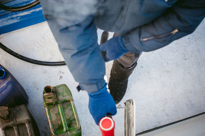 Low section of man filling can with fuel during winter