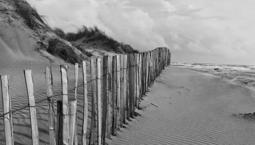 Wooden posts on beach against sky