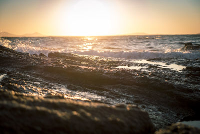 Rock formations at sea shore against sky during sunset