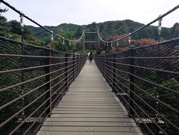 Rear view of people on footbridge against sky