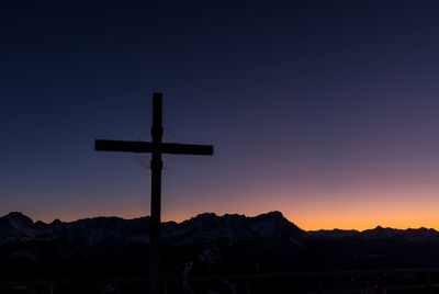 Silhouette cross against sky during sunset