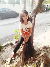 Portrait of happy girl on tree trunk