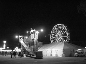 Illuminated ferris wheel against clear sky at night