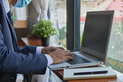 Midsection of man using laptop on table