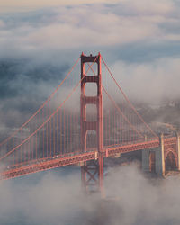 Golden gate bridge in city against cloudy sky